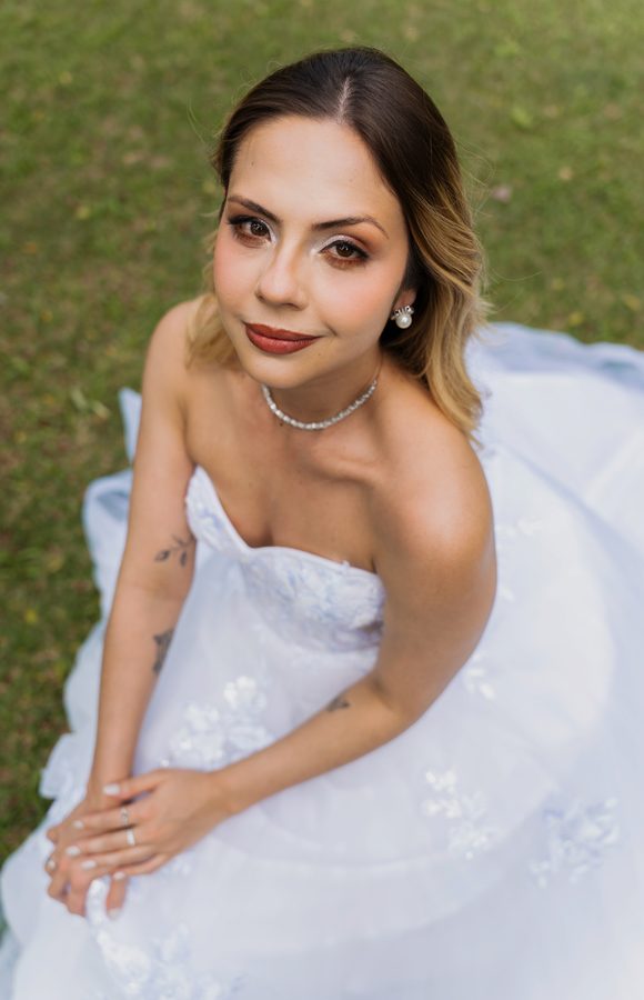 Retrato da noiva sentada no jardim, olhando para a câmera.